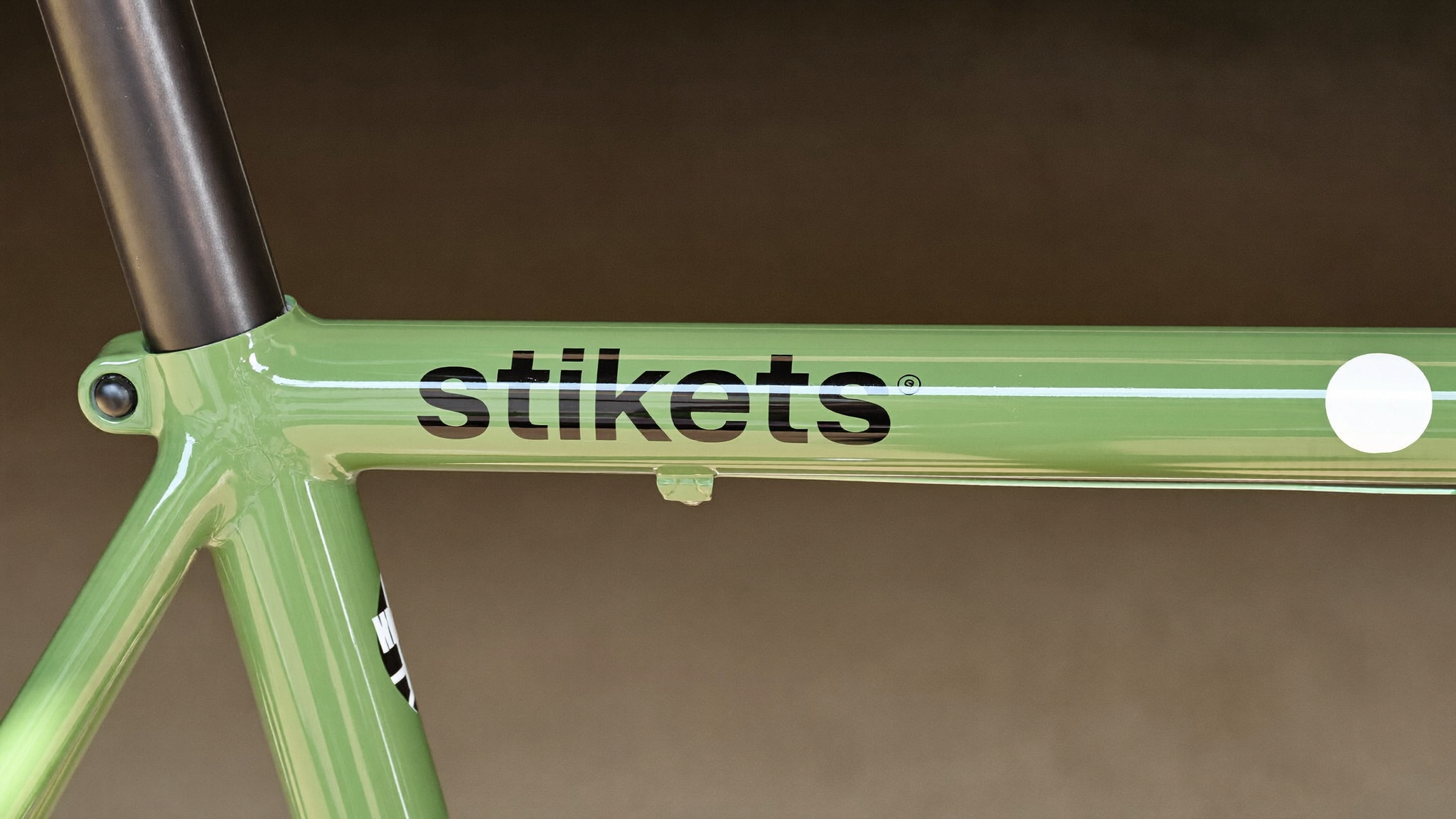 Tubo superior de una bicicleta verde con el nombre Stikets en vinilo negro aplicado directamente sobre la pintura