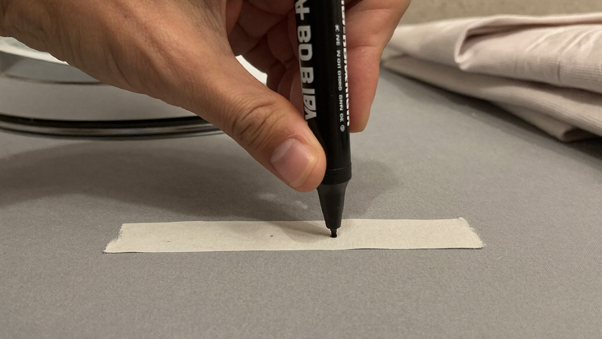 Rotulador permanente a punto de escribir sobre una cinta termoadhesiva en blanco