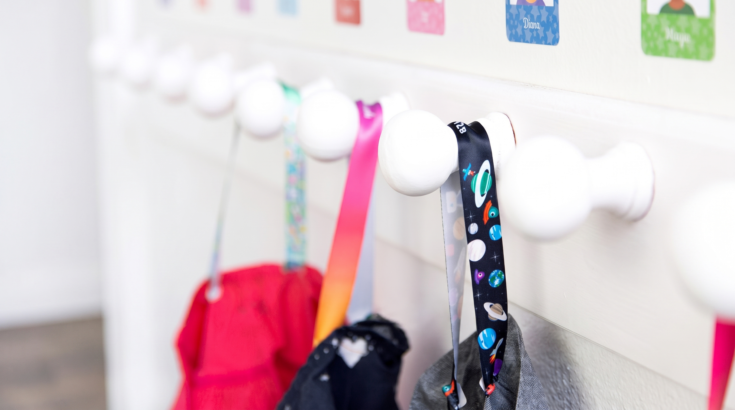 Cintas para colgar ropa de varios colores enganchadas en los percheros del cole