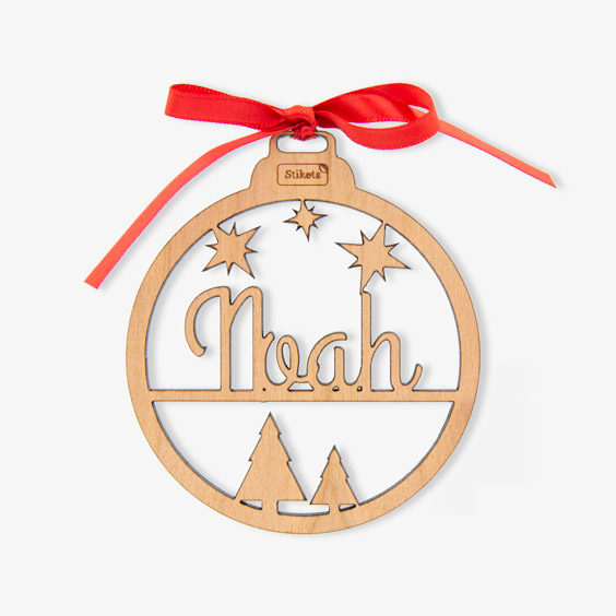 Bola de Navidad de madera calada con un nombre en lettering, estrellas y abetos, con lazo rojo
