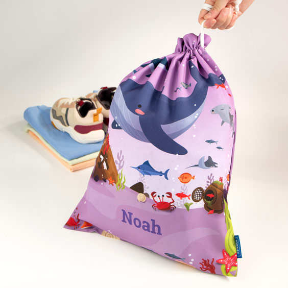 Bolsa de muda de ballena junto a ropa infantil doblada