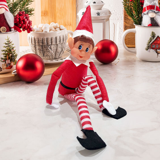 Elfo navideño travieso de Stikets sentado con las piernas de rayas estiradas
