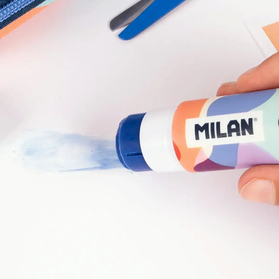 Barra de pegamento Milan aplicando adhesivo azul que desaparece al secarse