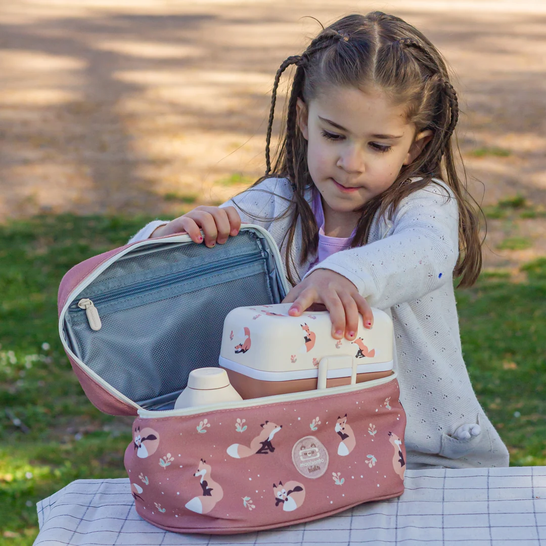 Niña colocando su fiambrera dentro de una bolsa térmica Monbento Frosty Fox al aire libre