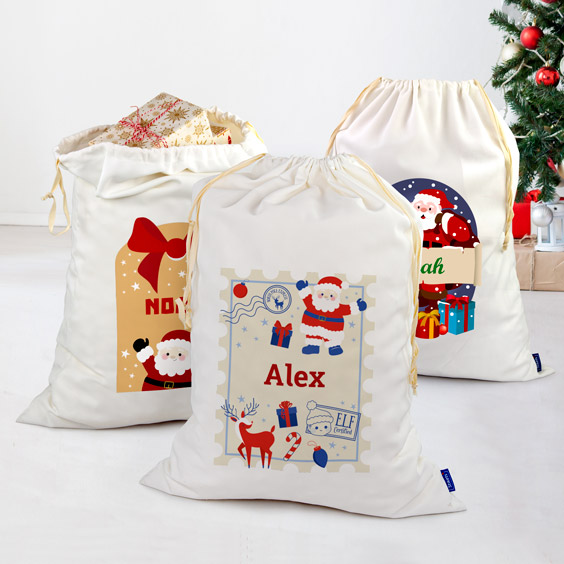 Tres sacos de regalos de Navidad blancos personalizados con diseños distintos y nombres diferentes