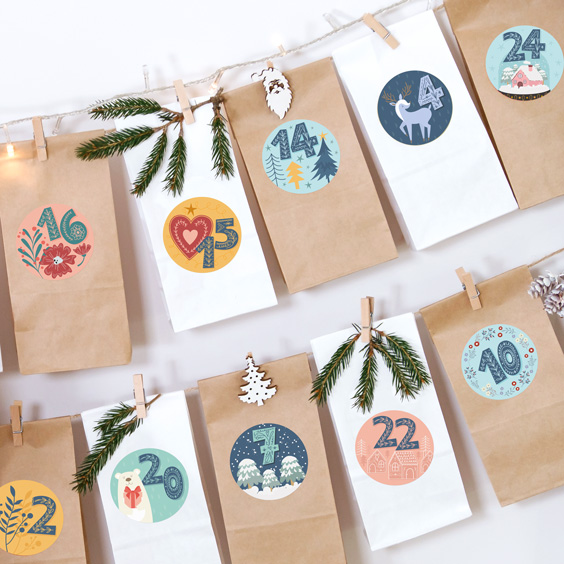 Guirnalda de bolsitas de papel colgadas con pinzas y cerradas con pegatinas redondas numeradas de calendario de Adviento