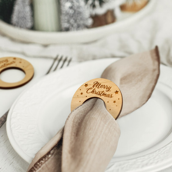 Servilletero navideño de madera con diseño fijo sujetando una servilleta sobre un plato blanco