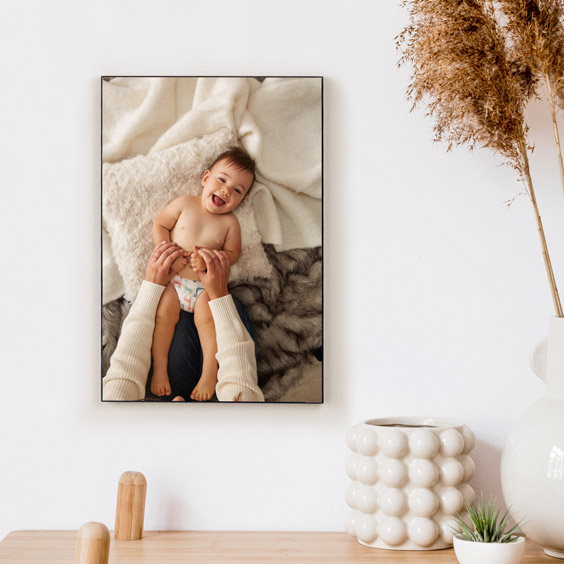 Portafoto de madera colocado en vertical sobre una cómoda, con un retrato de bebé